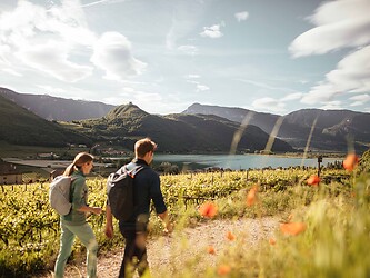 Frau und Mann bei Frühlingswanderung vorbei an See mit Bergpanorama