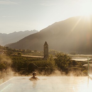 Frau genießt im Infinity Skypool die traumhafte Aussicht bei Sonnenaufgang