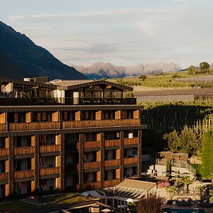 Hotelfassade mit Pool und Garten umgeben von der Bergwelt im Vinschgau