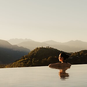 Frau genießt im Infinity Skypool den Dolomitenblick bei Sonnenaufgang