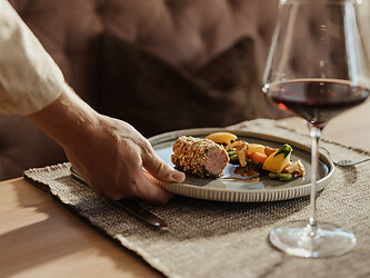 Servicekraft serviert das Abendessen mit einem Glas Rotwein