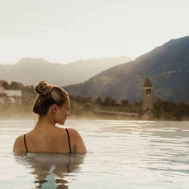 Frau im Infinity Sky Pool mit Thermalwasser und Blick über das Tal