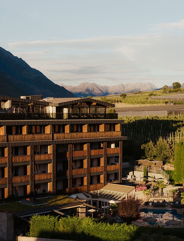 Hotelfassade mit Pool und Garten umgeben von der Bergwelt im Vinschgau